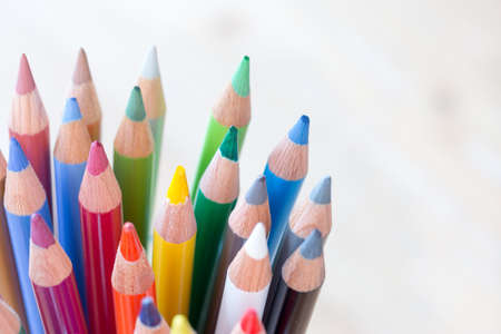 Colored pencils in a can on rustic wooden table, white backgroundの写真素材