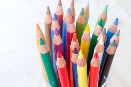 Colored pencils in a can on rustic wooden table, white backgroundの写真素材