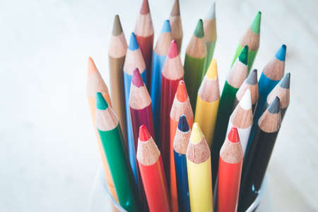 Colored pencils in a can on rustic wooden table, white backgroundの写真素材