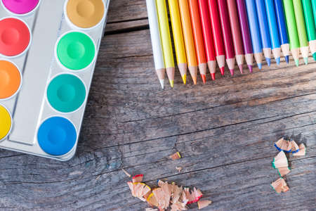 Set of multi-colored pencils, water colors and brushes on a rustically wooden table, copy spaceの写真素材