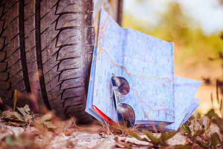 Car tire, sunglasses and roadmap on sandy ground, desertの写真素材
