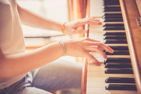 Young girl is practicing piano at home. Clipping of piano and hands.の写真素材