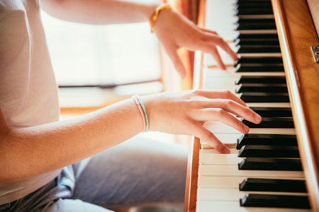 Young girl is practicing piano at home. Clipping of piano and hands.の写真素材