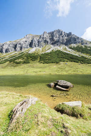 Lake with clear water in the foreground, rugged mountains in the backgroundの写真素材