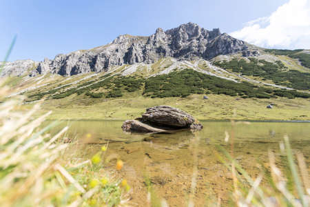 Lake with clear water in the foreground, rugged mountains in the backgroundの写真素材