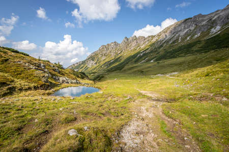 Idyllic mountain landscape in the alps: Beautiful scenery of meadow, mountains and blue skyの写真素材
