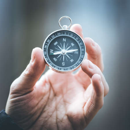 Man on an adventure is holding a compass in his hand for finding is routeの写真素材