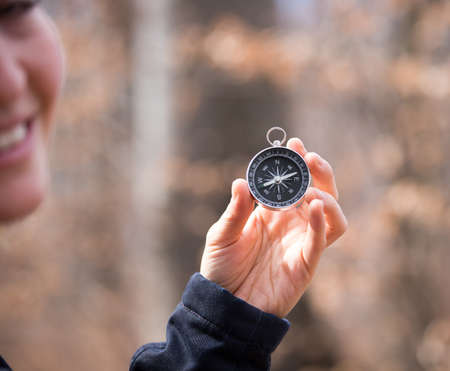 Girl on an adventure is holding a compass in her hand for finding is route, blurry face