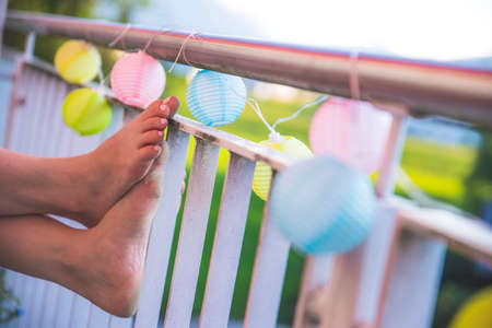 Relaxation / holidays on the terrace: Feet and colorful lampionsの写真素材