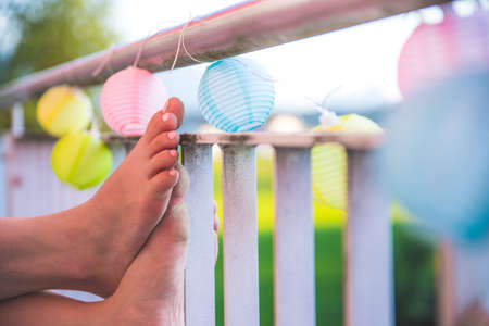 Relaxation / holidays on the terrace: Feet and colorful lampionsの写真素材