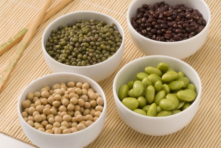 Assorted dried and fresh soybeans in white bowls の写真素材