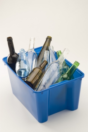 Glass bottles in a blue recycling bin. White background.の写真素材