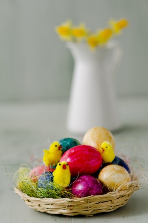 Toy chikens and painted Easter eggs in a basket  Focus on foreground の写真素材