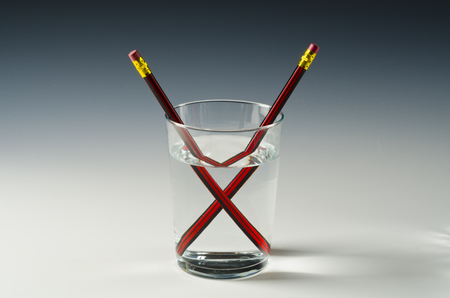 A pencil in a glass of water shows light refraction.