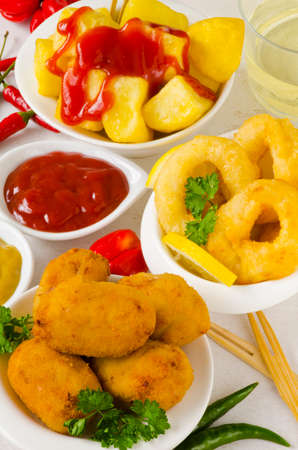 Spanish Tapas. Spicy fried potatoes in hot sauce, Ham Croquettes and Fried Squid Rings. Patatas bravas, Croquetas de Jamon, Calamares a la Romana.の写真素材