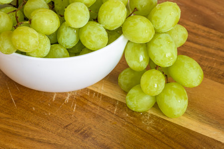 white grapes in a bowl on a wooden board