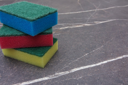 Three colored cleaning sponges on a dark marble backgroundの写真素材