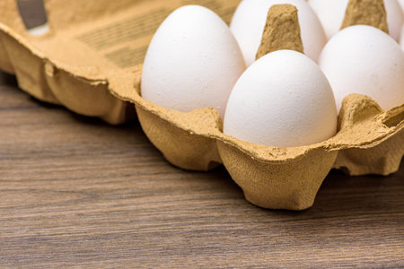 Close-up of free-range eggs in a cardboard egg carton on a dark walnut table