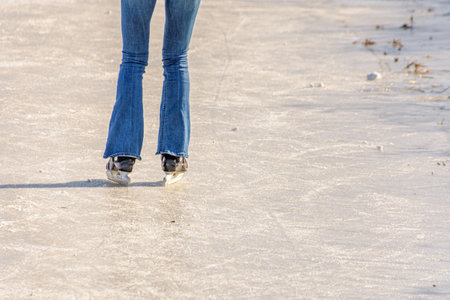 A young woman skates over a frozen ditch over the natural ice in the sun.の写真素材