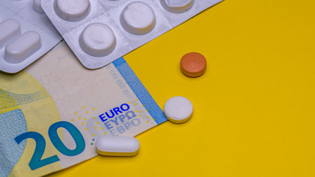 Medicines and euro banknote isolated on yellow background