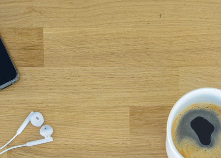 wooden office desk background with smartphone, cup of coffee and supplies. Top view with copy space,...
