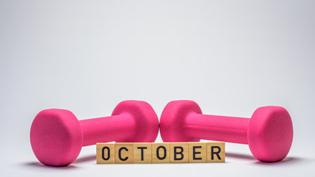 wooden blocks spelling 'October' in front of a pink dumbbells on a white background. This minimalist composition symbolizes fitness goals, motivation, and a fresh startの写真素材
