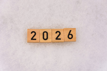 The number 2026 is made of wooden blocks on a snowy background. Textured background with snow. New...
