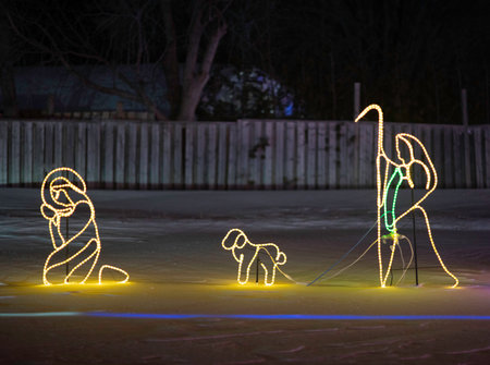 Illuminated Christmas scene with figures on a snowy night.の写真素材