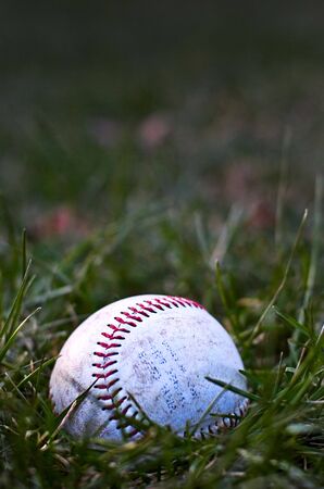 An abandoned baseball sits in the field, forgotten and alone as the evening draws near.