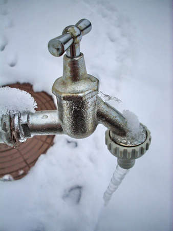 frozen faucet with the ice and snow in backgroundの写真素材