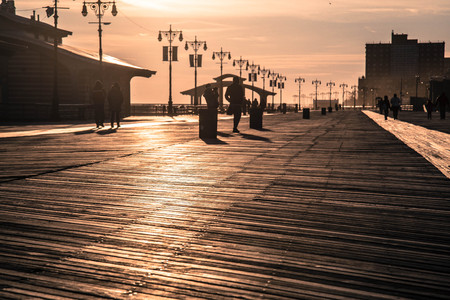 People walking on the boardwalk on Coney Island at sunsetの写真素材
