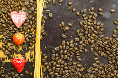 A heart with the letters BFF, incense sticks, strawberries and coffee beans on an old scratchy wooden surfaceの写真素材