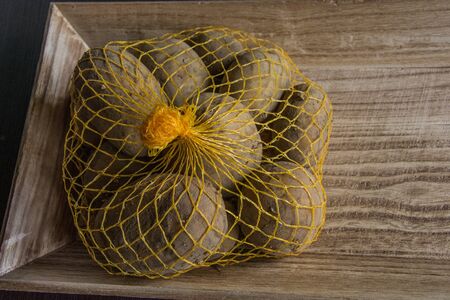 Raschel bag with potatoes on the woodの写真素材