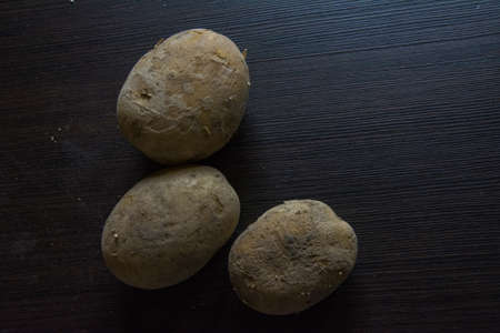Potatoes on black woodの写真素材