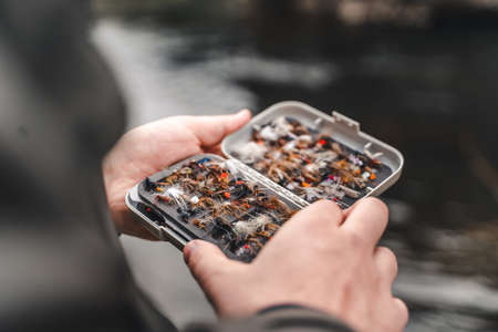 Fisherman holding fly fishing lures boxの写真素材