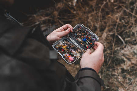 Fisherman holding fly fishing lures boxの写真素材