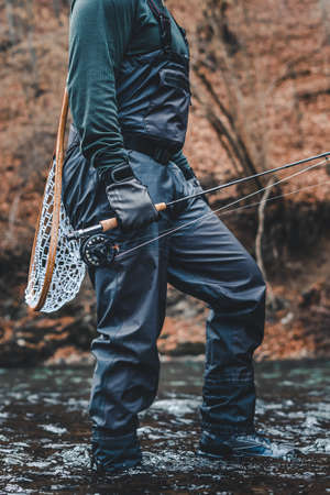 Fisherman fly fishing in river with rod, reel and landing net gearの写真素材