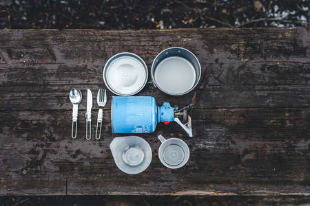 Gas camping, tourism and travel stove set with pot and cutlery on wooden tableの写真素材