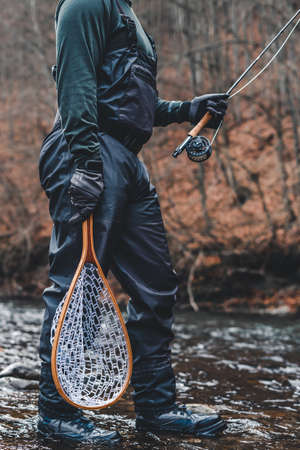 Fisherman fly fishing in river with rod, reel and landing net gearの写真素材
