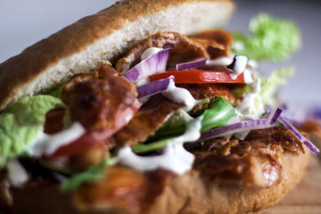 Fresh kebab burger with salad, red onion, tomatoes and sauce close upの写真素材