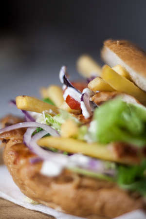 Fresh kebab burger with fries, salad, red onion, tomatoes and sauce blur backgroundの写真素材