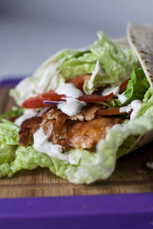 Fresh kebab wrap with salad, red onion, tomatoes and sauceの写真素材