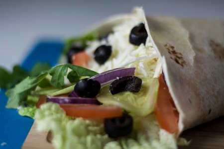 Vegetarian wrap made of cheese, onion, olives and salad close-upの写真素材