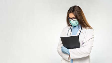 Young female caucasian doctor feel hopeless and sad. Holding documents in hands.の写真素材