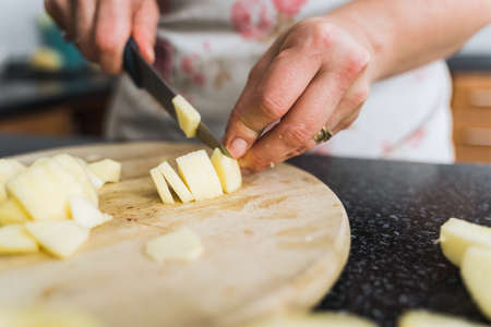 Closeup of young housewife cutting apples on wooden board for apple pie.の写真素材