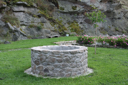 water well in garden in background rockの写真素材