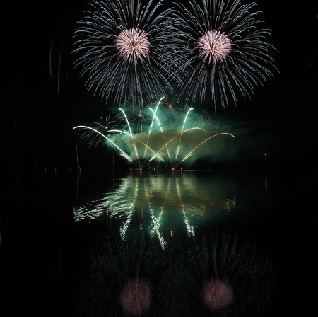 Colorful fireworks with reflection on lake and night sky in background.の写真素材
