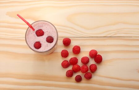 Smoothie from raspberries  in a glass and raspberries  on wooden tableの写真素材
