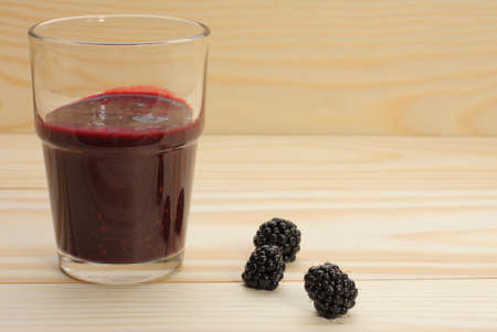 Smoothie from blackberries  in a glass and blackberries  on wooden tableの写真素材