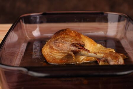 Roast duck in glass pan on wooden tableの写真素材